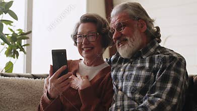 Happy mature couple using smartphone. Elderly grandfather and grandmother spend time having fun using smartphone, Middle