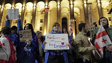 Tbilisi, Georgia - 12th May, 2024: Protestors hold up signs and flags during a nighttime demonstration expressing their