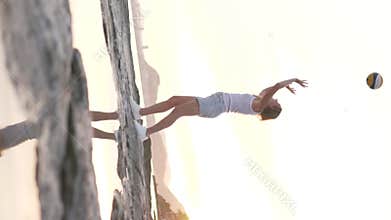 Vertical video, Female volleyball player kicking a volleyball at sunset by the sea
