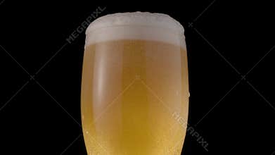 Glass of light beer on a black background.