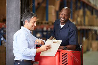 Fork Lift Truck Operator Talking To Manager In Warehouse