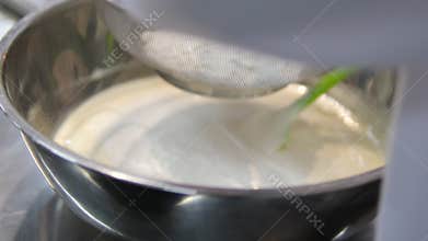 Add flour to. woman's hand mixes the dough with the added flour with a spoon. Making pastries at home.