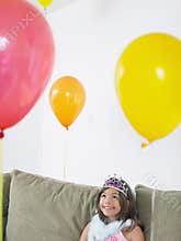 Girl Looking Up At Balloons On Sofa