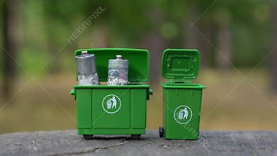 Hand in Blue Glove Disposing Batteries in Miniature Trash Bins