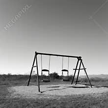 Abandoned swings in a desolate black and white playground