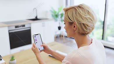 Caucasian woman shopping online using smartphone in modern home setting
