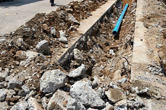 Excavation site with trench, stones, and a blue pipe