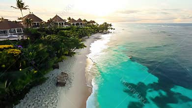 Luxurious beachfront villas surrounded by lush tropical gardens, with vibrant flowers and palm trees along a pristine