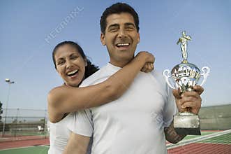 Mixed doubles Tennis Players standing in tennis court holding trophy portrait