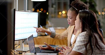 Young African American woman and biracial woman collaborate in a business office