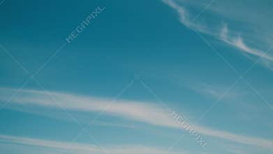 Floating fluffy cirrus clouds. Beautiful sunny blue sky with wispy smoky white.