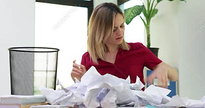 Businesswoman holding a trash can and looking for lost document