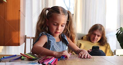 Girl takes markers from plastic box against man in room