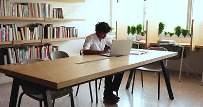 Indian student doing assignment, prepare essay using laptop and internet