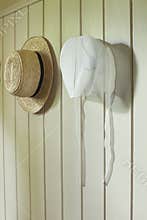 Amish bonnet and straw hat hanging on wall