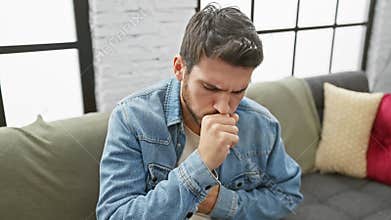 A young hispanic man coughing indoors, looking unwell in a casual setting, denoting sickness or allergies at home