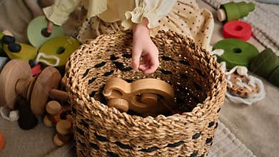 Little girl's hands put wooden toys in the basket.