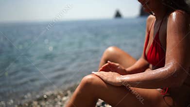 Woman beach sea. Women's legs by the sea and women's hands are smeared with sunscreen. Slow motion video of a