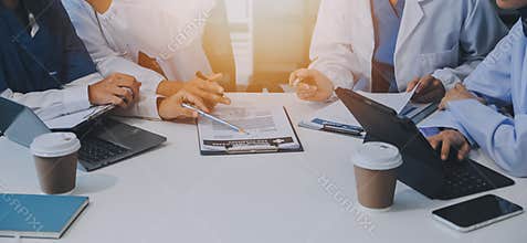 Team of medical staff having morning meeting in boardroom. Doctors and nurses looking at digital tablet