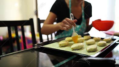 Cook greases the buns on a baking sheet with a brush with a beaten egg