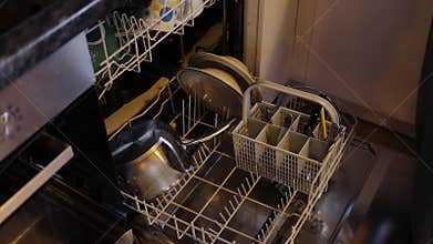 Man puts kitchen utensils to dishwasher. Slow