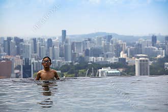 Boy in swimming pool, Singapore skyline in the back