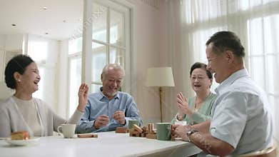 two happy senior asian couples playing leisure game at home