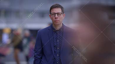 A man is standing still in a busy urban street amidst the blur motion of passersby