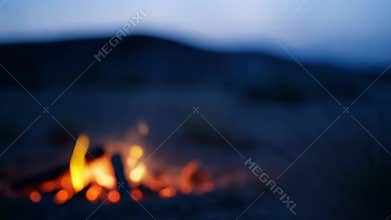 The silence of the desert is interrupted only by the occasional crackle of the campfire and the soft rustle of the wind
