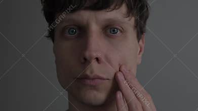 Close up of young man touching single pimple on face, acne spot and skin imperfection, male skincare, real life.