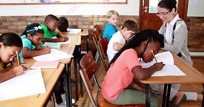 Pupils working hard during class with teacher smiling at camera