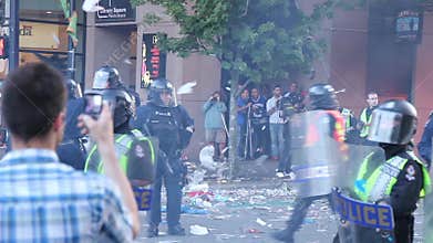 Small tornado of debris fly around riot officers