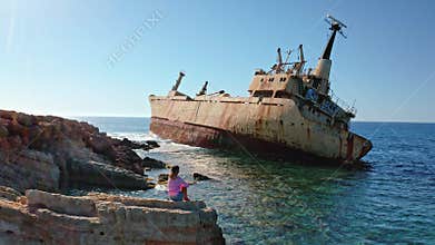 Woman sitting on rocks viewing Edro III shipwreck in Cyprus