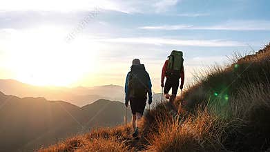 Two hikers backpacking at sunrise on mountain trail with scenic valley view