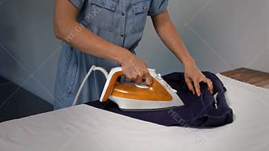 Unrecognizable woman ironing a man's shirt at home. Domestic life chore.