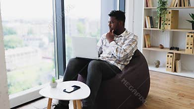 Man working on laptop while seated in a modern cozy interior space
