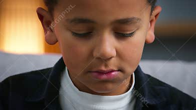 Close up sad upset little African American boy thinking pensive sadness frustrated child looking down stressed ethnic