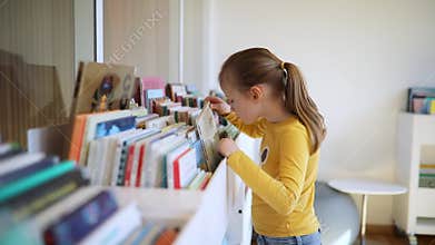 Adorable schoolgirl in municipal library reading a book
