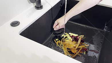 Kitchen disposer process. Hand cleaning vegetable peel leftovers in sinkhole