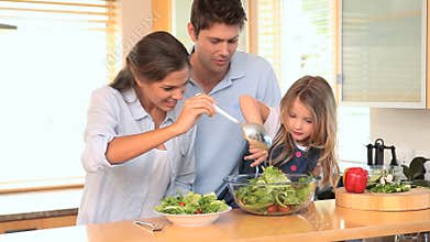 Family in the kitchen making a salad together