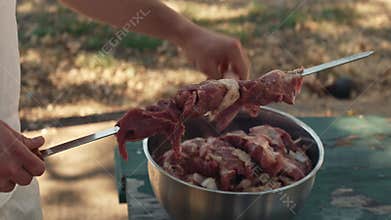 Marinated meat with onion being skewered for barbecue