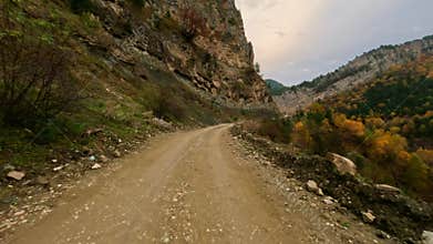 A sunny day, high-speed driving on a dirt road in the mountains. View from the car windshield. Shot with an action camera without
