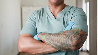 Confident Medical Professional with Tattoos in Blue Scrubs Standing with Arms Crossed