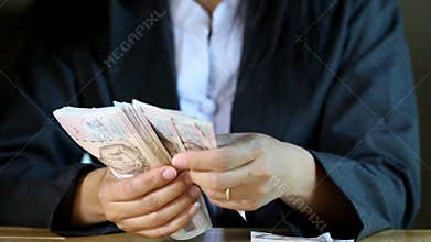 Business woman count one thousand baht bill note.