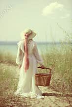 Vintage woman at the beach with picnic basket