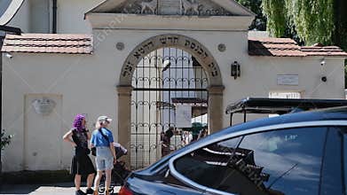 Pedestrians passing an arched gate with Hebrew letters at historic Jewish quarter entrance in Krakow Poland