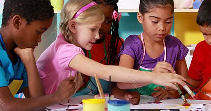 Preschool class painting at table in classroom