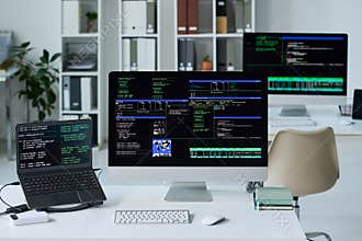 Office Desk Displaying Computer Screens Running Programming Code
