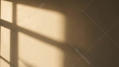 Geometric window shadow cast by warm sunlight on a blank wall, creating an abstract and serene pattern of light and shade