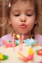 Little girl blowing birthday candles